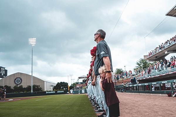 Arkansas coach Dave Van Horn consoles a child during the national anthem prior to a game against Texas A&M on Saturday, May 18, 2019, in College Station, Texas.