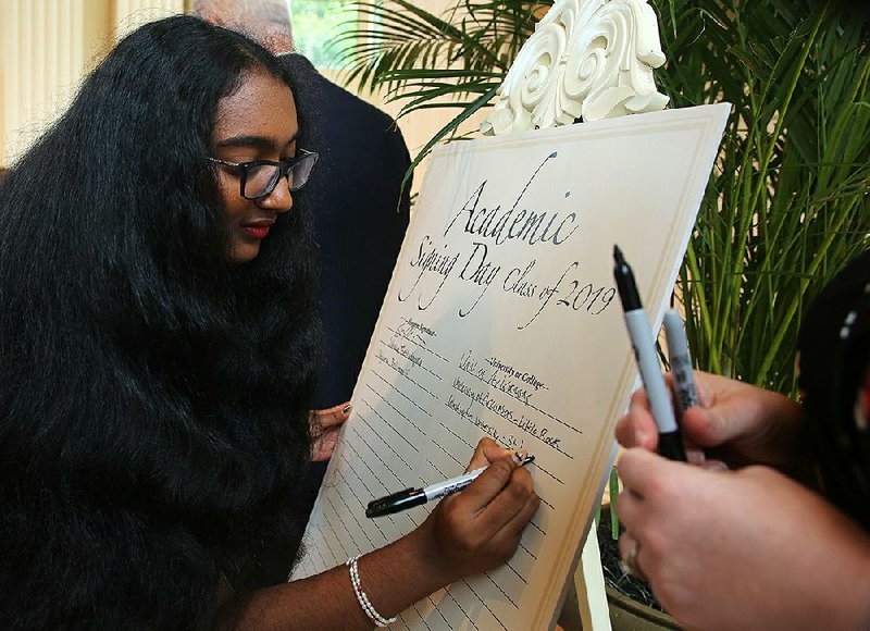 Little Rock Central High senior Maghana Bollimpalli signs her name as part of the annual Little Rock School District academic signing day at the Governor’s Mansion in Little Rock on Monday. About 101 students, which is a new record for the event, were celebrated for their academic excellence. 