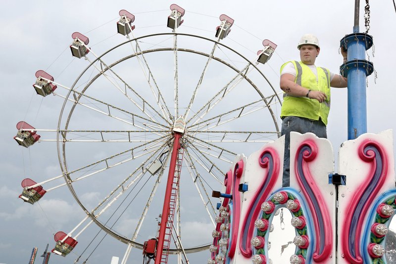 Dausen Rivas with Pride Amusements assembles a carousel Tuesday on the grounds at Parsons Stadium in Springdale. The Spring Carnival begins Wednesday and runs through Sunday. NWA Democrat-Gazette/DAVID GOTTSCHALK