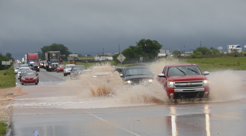 Vehicles drive through floodwater on US Highway 66 following heavy rains Tuesday, May 21, 2019, in El Reno, Okla. (AP Photo/Sue Ogrocki)