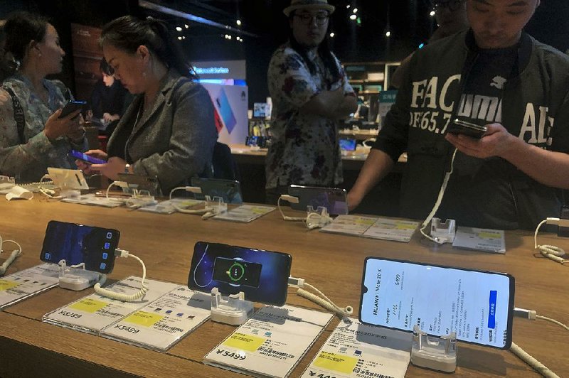 People try out Huawei Technologies smartphones Monday at an electronics store in Beijing. The U.S. Commerce Department says it will delay security restrictions on Huawei for 90 days, allowing it to continue doing business with American suppliers to prevent disruption to mobile networks. 