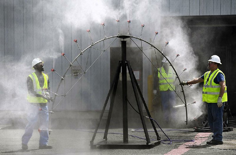 Workers test a spray to be used for controlling contaminated dust in the decommissioning process at Vermont Yankee Nuclear Power Station in Vernon, Vt., one of several shuttered nuclear power plants in the U.S. that are being bought by cleanup companies that promise to speed up the decontamination process. 