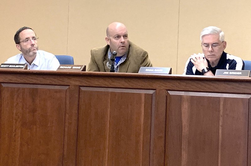 NWA Democrat-Gazette/MARY JORDAN Planning Commission members Scott Eccleston (from left), Richard Binns and Dana Davis examine plans Tuesday for city development projects during meeting in Bentonville.