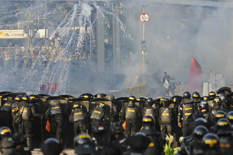 An Indonesian riot police officer fires tear gas Wednesday to disperse supporters on presidential candidate Prabowo Subianto during a rally in Jakarta. 