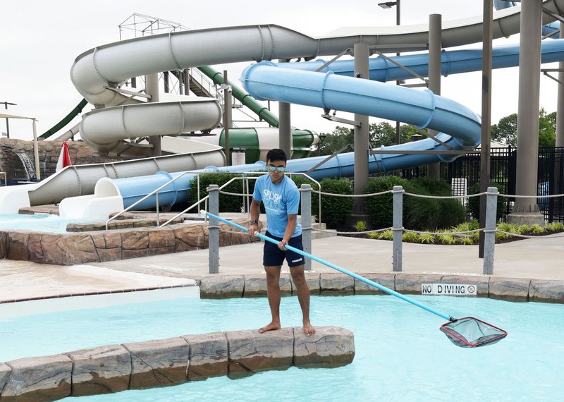Jordan Tong, a lifeguard at the Rogers Aquatics Center, works Wednesday getting the center ready for opening day and the summer season. The aquatics center at Dock Wheeler Park, 1707 S. 26th St., opens at 11 a.m. Saturday. NWA Democrat-Gazette/FLIP PUTTHOFF