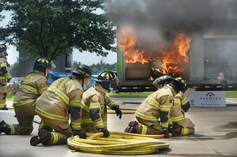 Siloam Springs firefighters wait Thursday to extinguish a fire as it burns in a metal structure during a demonstration of residential fire sprinklers organized by the Northwest Arkansas Association of Fire Marshals and Siloam Springs Fire Department at the department's Station One. Visitors and representatives from area fire agencies saw the affect a sprinkler has on a working fire and were able to compare it with an uncontrolled fire. NWA Democrat-Gazette/ANDY SHUPE
