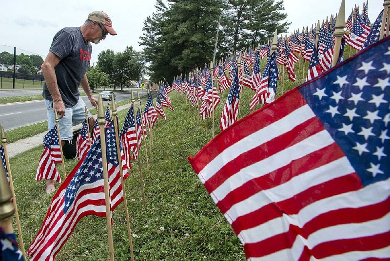 Randy Hartsock places American flags on the embankment outside of American Legion Hackler-Wood Post 145 on Thursday, in Bristol, Tenn. in preparation for Memorial Day weekend. 