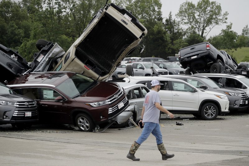 A worker walks past tornado-damaged Toyotas at a dealership in Jefferson City, Mo., Thursday, May 23, 2019, after a tornado tore though late Wednesday. (AP Photo/Charlie Riedel)