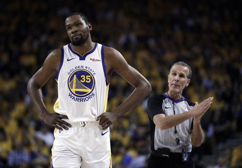 FILE - In this Wednesday, May 8, 2019, file photo, Golden State Warriors' Kevin Durant, left, walks away from referee Ken Mauer during the first half of Game 5 of the team's second-round NBA basketball playoff series against the Houston Rockets in Oakland, Calif. Durant is yet to progress to on-court work in his recovery from a strained right calf and won't be ready to return for Golden State in Game 1 of the NBA Finals on May 30. (AP Photo/Ben Margot, File)