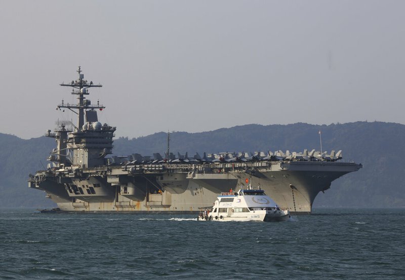In this March 5, 2018, file photo, a Vietnamese passenger boat sails past U.S. aircraft carrier USS Carl Vinson as it docks in Danang bay, Vietnam. A U.S. sailor has pleaded guilty to espionage and sentenced to three years after admitting he took classified information about a Navy's nuclear-powered warship and planned to give it to a journalist and then defect to Russia officials said Friday, May 24, 2019. Jeff Houston of the Naval Criminal Investigative Service or NCIS said that U.S. Navy Petty Officer 2nd Class Stephen Kellogg III wished to publish an expose on waste within the military and admitted he wanted to share the information with Russians. Kellogg, who joined the Navy in 2014 served aboard the USS Carl Vinson from 2016 to 2018. (AP Photo/Hau Dinh, File)
