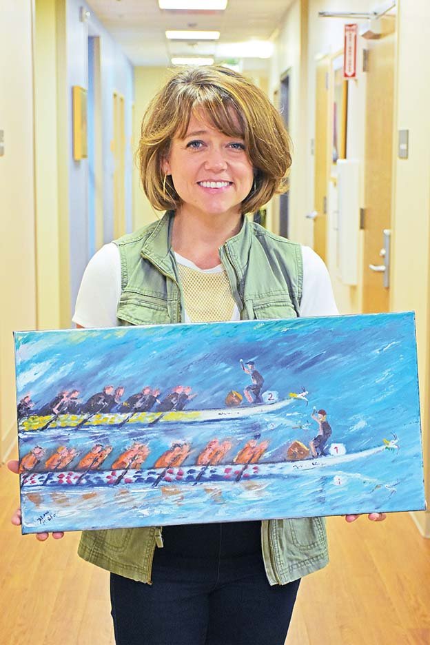 Jennifer Long, executive director of the Children’s Protection Center in Little Rock, holds original artwork by David McGhee of Little Rock that depicts the River Cities Dragon Boat Festival. The seventh annual event is scheduled for June 14 and 15 at Lake Willastein in Maumelle, and race day will begin at 9 a.m. June 15. Proceeds will go to the nonprofit Children’s Protection Center.