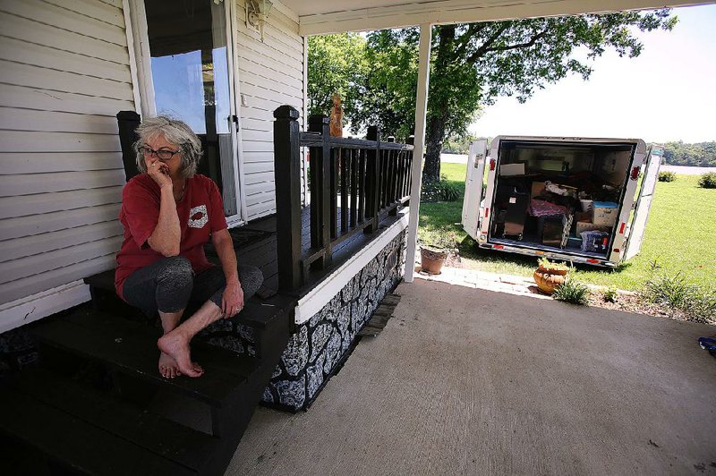 Jan Sloss takes a break from moving belongings out of her house near the Arkansas River in Perry County. “I’ve lived on the river long enough to know when it’s time to go,” she said. More photos are available at arkansasonline.com/525floodprep/