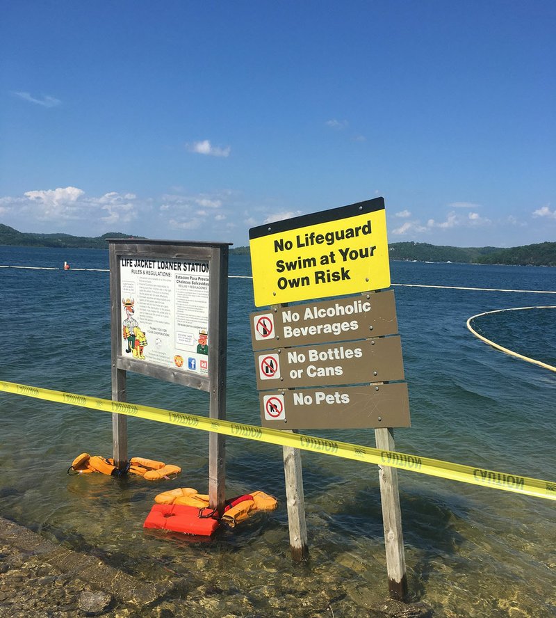 NWA Democrat-Gazette/FLIP PUTTHOFF Caution tape Friday cordons off the Rocky Branch swim beach. The beach is closed to swimmers because of high E. coli bacteria levels.
