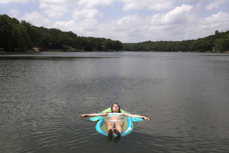 Megan Townsend, 17, of Centerton lays out Friday on a raft at the Lake Avalon dock in Bella Vista. NWA Democrat-Gazette/CHARLIE KAIJO