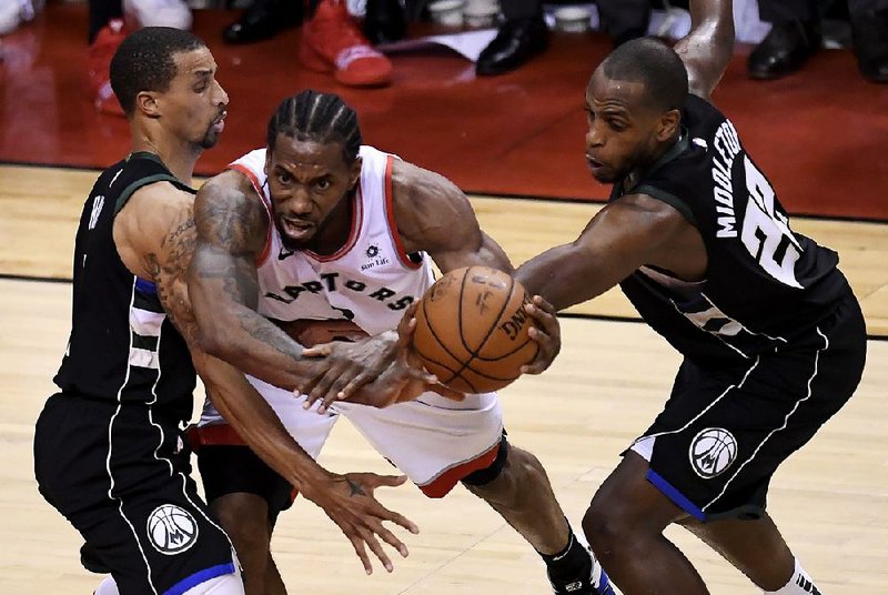 Toronto Raptors forward Kawhi Leonard (center) works between Milwaukee’s George Hill (left) and Khris Middleton during the second half of Game 6 of the Eastern Conference finals Saturday in Toronto. Leonard had 27 points, 17 rebounds and 7 assists to lead the Raptors to a 100-94 victory.