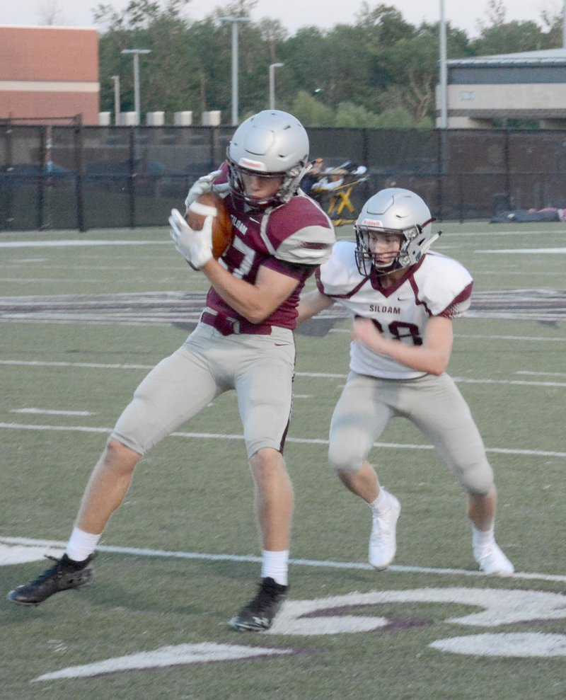 Graham Thomas/Siloam Sunday Siloam Springs senior Tanner Broyles hauls in a catch as Tyler Johnson steps up to make a tackle during the annual Maroon-White spring game held May 17 at Panther Stadium.