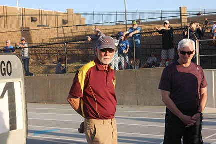 The Sentinel-Record/James Leigh--Lake Hamilton head track and field coach Karl Koonce, left, listens as his accomplishments are read prior to his &quot;final lap&quot; around the track near the end of the Lake Hamilton Invitational track meet on April 12, 2019. Koonce is The Sentinel-Record's Spring Sports Coach of the Year.