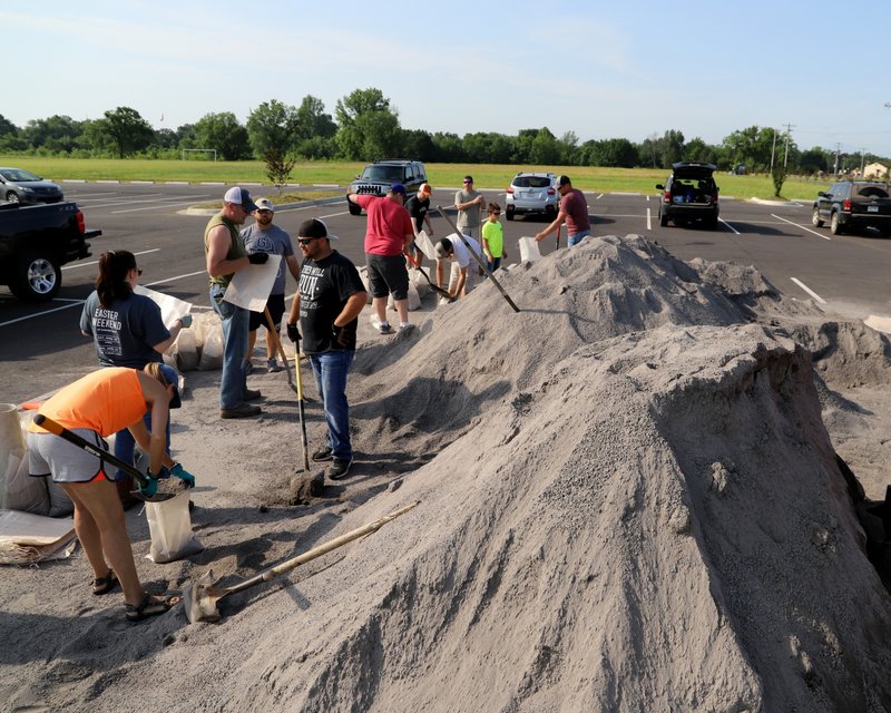 Volunteers fill sand bags at the soccer field parking lot in Chaffee Crossing, Ark., Saturday, May 25, 2019, for distribution throughout the area for flood prone areas around homes. (Jamie Mitchell/The Southwest Times Record via AP)