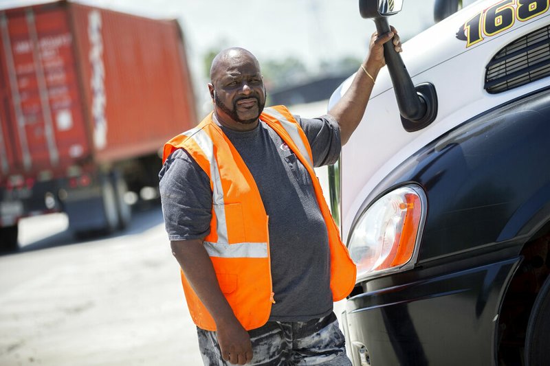 In this Wednesday, May 22, 2019 photo, Leon Brown stands by his tractor-trailer after making a delivery from a distribution center to the Port of Savannah, in Garden City, Ga. Brown is trusted enough to drive a tractor-trailer inside one of the nation's busiest seaports more than six years after being released from prison. But he's not allowed to vote in Georgia because of a law rooted in the years after the Civil War when whites sought to keep blacks from the ballot box. (AP Photo/Stephen B. Morton)