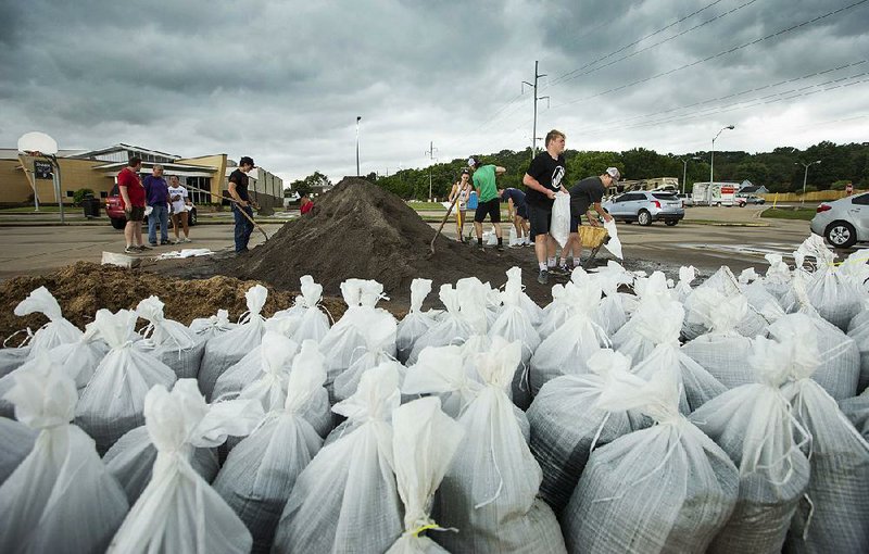 Volunteers, including members of the Greenwood High School football team, fill sandbags Wednesday at East Side Baptist Church in Fort Smith. They also helped load them into vehicles.