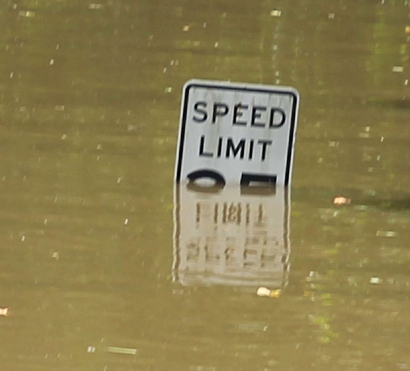 Water covers a speed limit sign Wednesday on a road in the Island Harbor Estates neighborhood of Pine Bluff. 