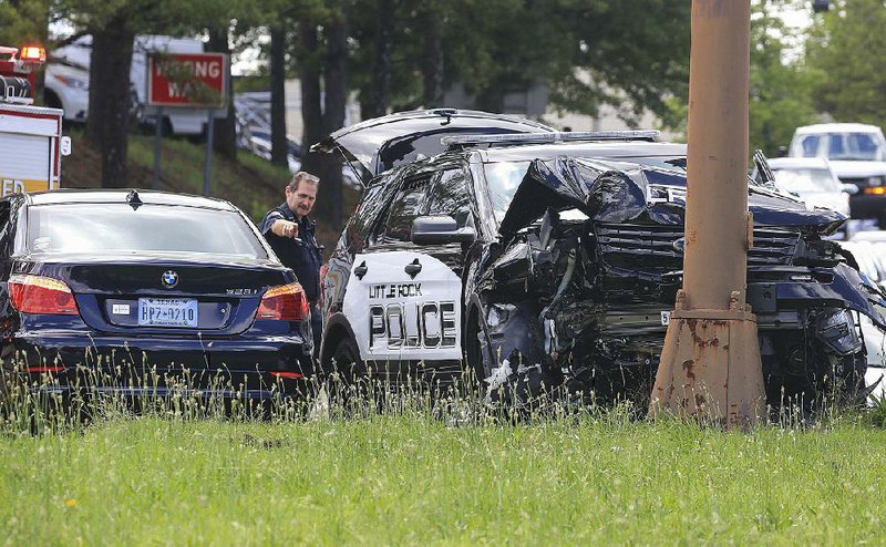 A Little Rock police officer investigates a crash Thursday involving a patrol car at West Eighth and South Pine streets. The patrol car and another vehicle collided as the police officer driver was heading to a reported shooting on Rebsamen Park Road. 