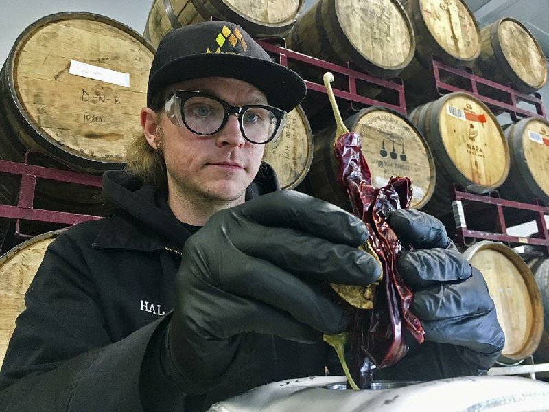 Hal McConnellogue, of Drake’s Brewing Co. in San Leandro, Calif., works on putting chipotle peppers into a cask used to infuse beer with unique flavors. 