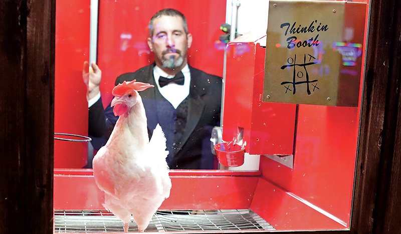 The Sentinel-Record/Richard Rasmussen CHICKEN CHALLENGE: Kelly Boger, operator of the Casino Chicken company, puts Ginger the chicken into the Chick-Tac-Toe booth at Oaklawn Racing Casino Resort on Friday as the Red Coat Ambassadors cut the ribbon on the new promotion.