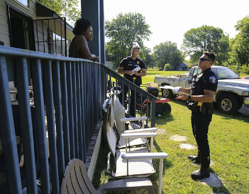 North Little Rock police officers Nick Stewart (center) and Alex Santucci talk with Joyce Martin on Saturday at her home in the Dixie Addition neighborhood as they go door to door to give residents evacuation information. More photos are available at arkansasonline.com/62flood/ 