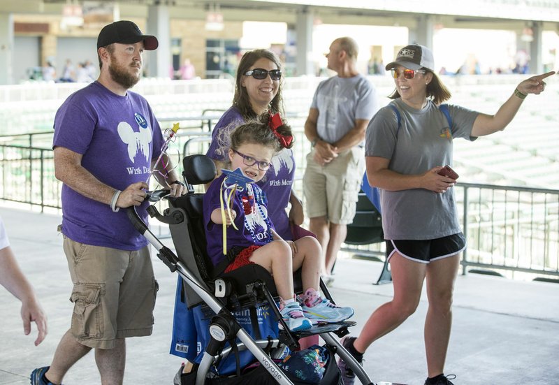 NWA Democrat-Gazette/BEN GOFF  @NWABENGOFF Aubree Shaw, 7, of Springdale, who had her wish granted to visit Disney World this year, takes part Saturday in the walk with father Derrick Shaw (from left), mother Audra Shaw and friend Heather Meador of Springdale during the annual Walk for Wishes Northwest Arkansas at Arvest Ballpark in Springdale. The event is a fundraiser for Make-A-Wish Mid-South, helping the organization grant wishes for children with life-threatening medical conditions.