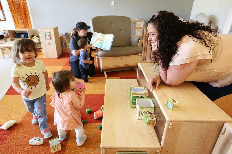 Sunny Lane, director of development at the Helen Walton Children’s Enrichment Center in Bentonville, visits with students Thursday in a preschool classroom. 