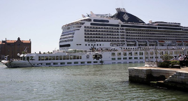 A cruise liner towers over a damaged tourist riverboat Sunday in Venice, Italy. A different cruise ship had slammed into the riverboat Sunday morning, injuring several people aboard the smaller vessel. 