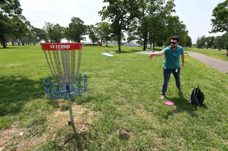NWA Democrat-Gazette/J.T. WAMPLER Nathan Brown of Fayetteville plays a round of disc golf May 23 at Kathleen Johnson Memorial Park in Lowell. Brown works in Lowell and plays disc golf on his lunch break. The city is turning donated land into a park that will include several nonprofit groups, a veterans memorial, a fire station and a walking trail connecting to the Razorback Greenway.
