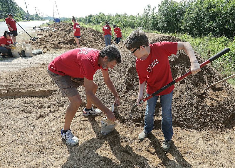 Drew Bunten (left) and his grandson, Gabe Jackson, fill sandbags Monday morning in the Dixie Addition in North Little Rock. They were with a church group volunteering to fill bags. More photos are available at arkansasonline.com/64flooding/. 