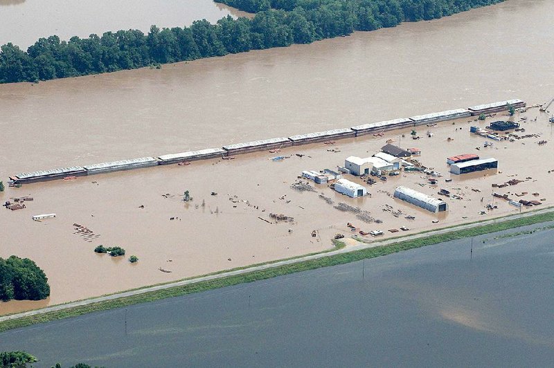 Eight river barges are lined up next to the bank of the flooded Arkansas River on Monday at the Rasmussen Group yard in Jefferson County. All barge traffic on the river has been halted until further notice, according to the U.S. Army Corps of Engineers.