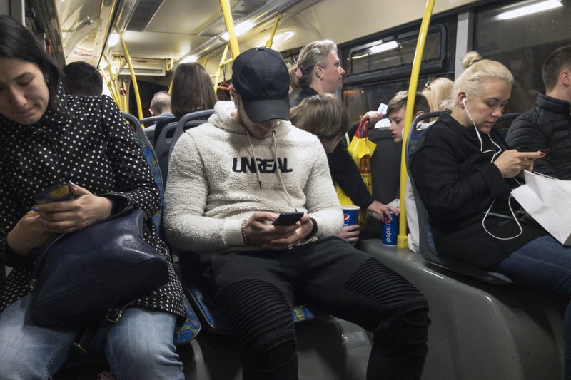 In this photo taken on Thursday, May 16, 2019, passengers look at their smartphones as they ride a bus in Moscow, Russia. Russia's communications regulator says that Tinder is now required to provide user data to Russian intelligence agencies. The Russian Communications Oversight Agency on Monday, June 3 published a new list of online services operating in Russia that are required to provide user data on demand to Russian authorities, including the FSB security agency. (AP Photo/Alexander Zemlianichenko)