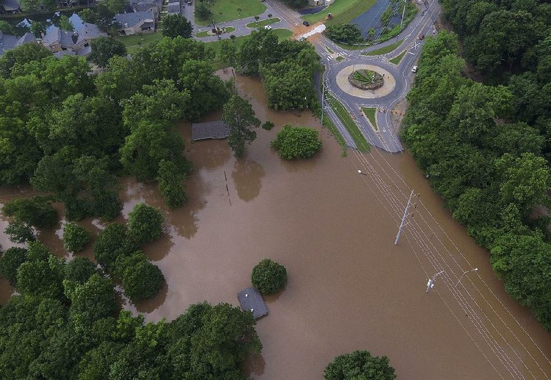 In this file photo Arkansas River floodwaters flow near the roundabout at Rebsamen Park Road and Riverfront Drive in Little Rock on Tuesday afternoon. The road is barricaded to keep out motorists for their own safety. 
