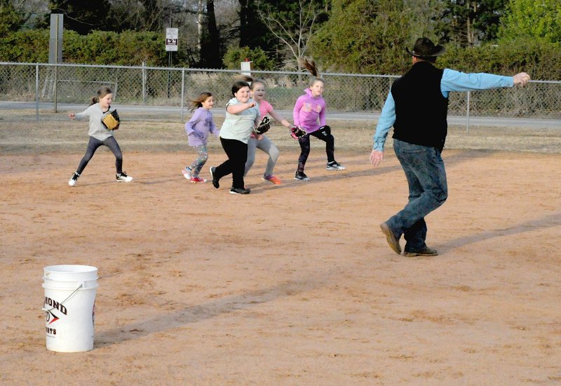 MARK HUMPHREY ENTERPRISE-LEADER A group of young softball players from the Little Ladies (Lincoln Girls T Ball) eagerly respond to coach Grant Keenen instructing them in the basics of fielding. The girls compete in the Washington County Civic League.