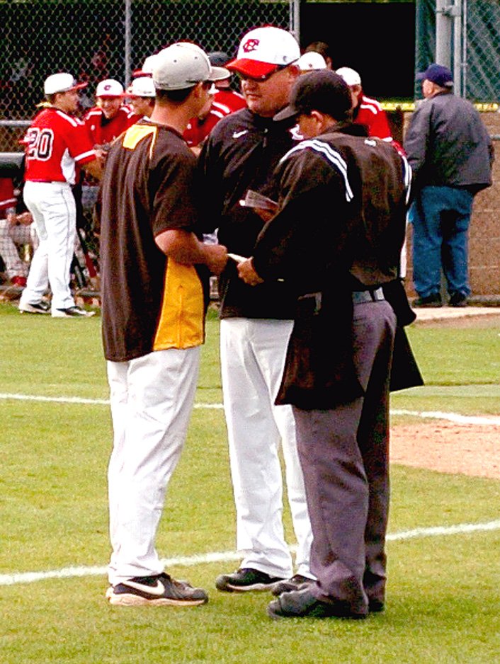 MARK HUMPHREY ENTERPRISE-LEADER Prairie Grove coach Mitch Cameron and Farmington coach Jay Harper confer with the plate umpire during a rivalry baseball game on April 27. 2015. The Tigers beat Farmington, 12-9, in that contest but haven't won since without Cameron, who rejoins Prairie Grove after four seasons at Rogers Heritage.
