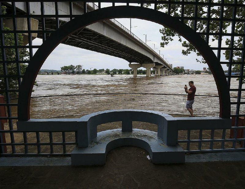 Steve Crowe of Little Rock gets video footage Wednesday of the swollen Arkansas River from a vantage point near the Belvedere in Little Rock’s Riverfront Park.
