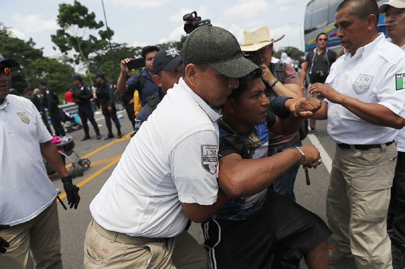 Mexican immigration authorities detain a migrant Wednesday near Metapa in Chiapas state during a raid on a caravan that had crossed the Guatemalan border earlier in the day. 