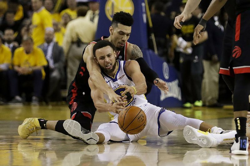 Danny Green (top) of the Toronto Raptors and Stephen Curry of the Golden State Warriors fight for a loose ball Wednesday night during Game 3 of the NBA Finals. The Raptors defeated the Warriors and lead the series 2-1. 