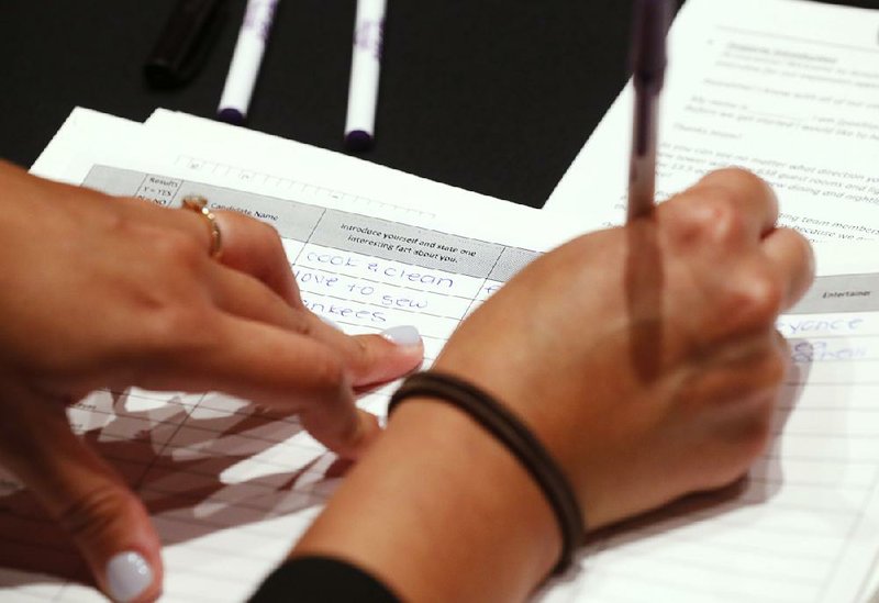 A worker writes down answers from job applicants during a job fair Tuesday in Hollywood, Fla.