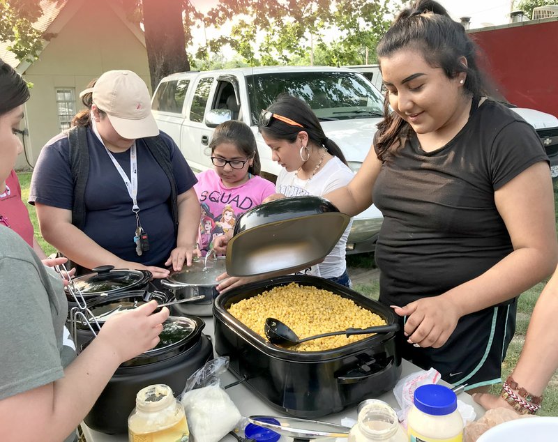 Sally Carroll/McDonald County Press The Noel Betterment Association will kick off a second season of First Fridays this Friday at 5 p.m. on Main Street. Last year's event featured some good, home-cooked Mexican food. Julissa Madrigal (left), Yarely Madrigal and Maria Esquibel prepare some food as Melisa Rubi stirs a pot of corn. This year's First Fridays will again feature delicious food, vendors, crafts, live music and family-friendly fun. Admission is free.