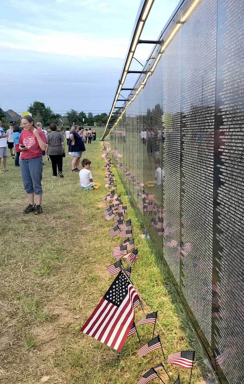 Sally Carroll/McDonald County Press People of all ages view The Wall That Heals, a traveling exhibit that resembles the Vietnam Veterans Memorial in Washington, D.C. Downtown Bentonville hosted the exhibit over Memorial Day weekend. A mobile education center featured a video highlighting area veterans, including those from McDonald County.