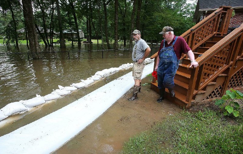 David Binz (right) and his son-in-law, David Woodall of Quitman, check the sandbag wall Thursday around Binz’s home on Lake Conway in Mayflower. Water was seeping toward the house. “I’ve done everything I can, all I can do is wait now,” Binz said. More photos are available at arkansasonline.com/67flooding/ 