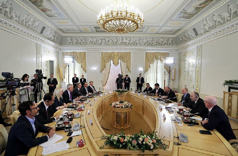 Russian President Vladimir Putin (third right) speaks Thursday during a meeting with heads of the world’s leading news agencies at the St. Petersburg International Economic Forum. 