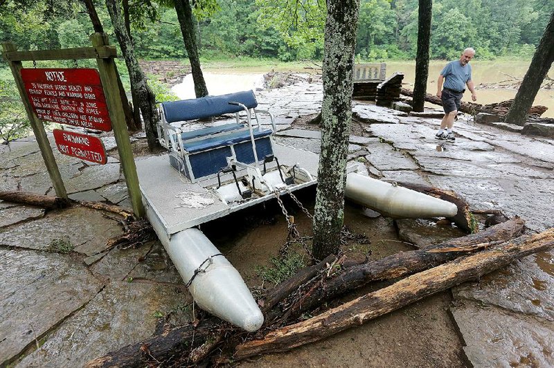 A washed-up pontoon paddleboat sits in the trees Friday at Devil’s Den State Park after heavy rains caused flash flooding on Lee Creek, which runs through the park in Washington County. 