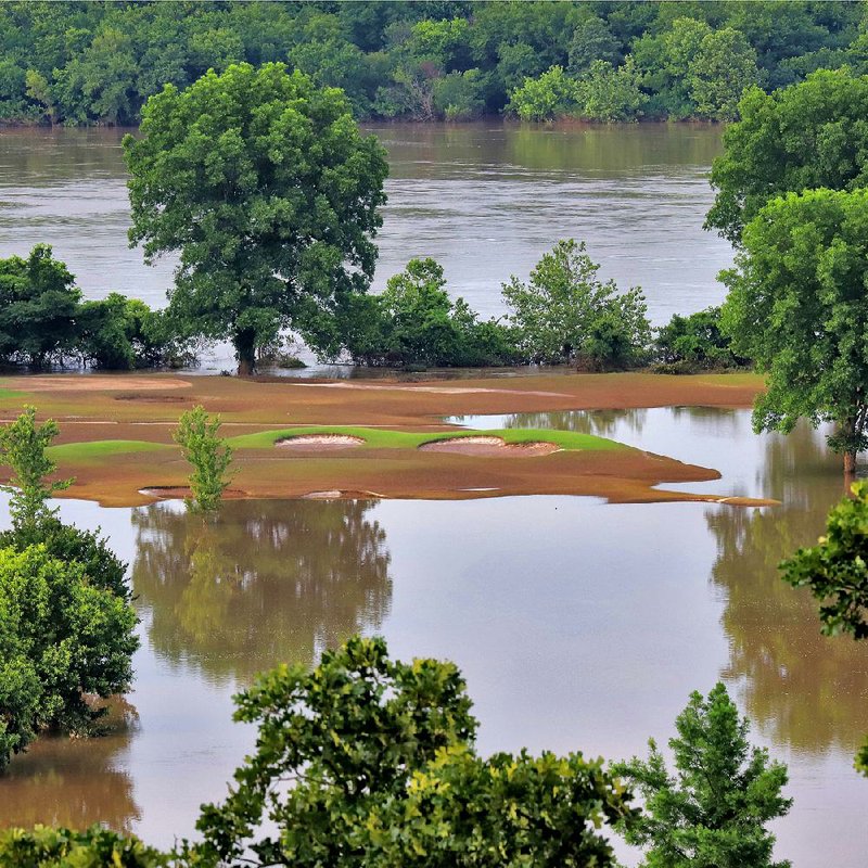 The Arkansas River flows in the background Saturday as its floodwaters still cover sections of Little Rock’s Rebsamen Golf Course. Access to the golf course and Murray Park remains blocked. Across the river in North Little Rock, much of Burns Park and the Arkansas River Trail are still under water.