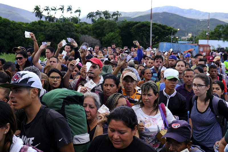 Venezuelans show their IDs on Saturday as they wait to cross the reopened Simon Bolivar International Bridge into Cucuta, Colombia.